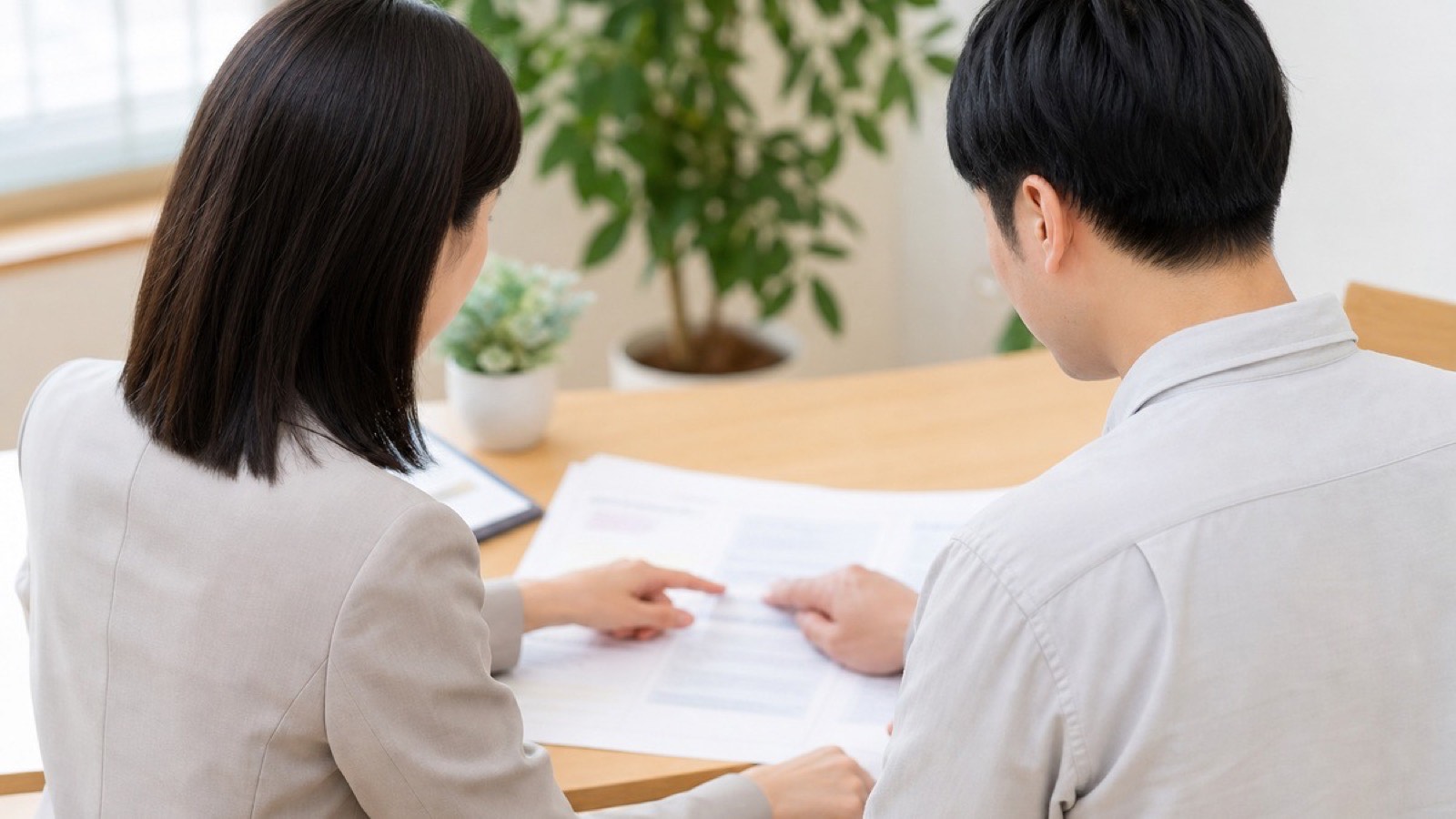 面談室で資料を見ながら相談する男性とカウンセラー