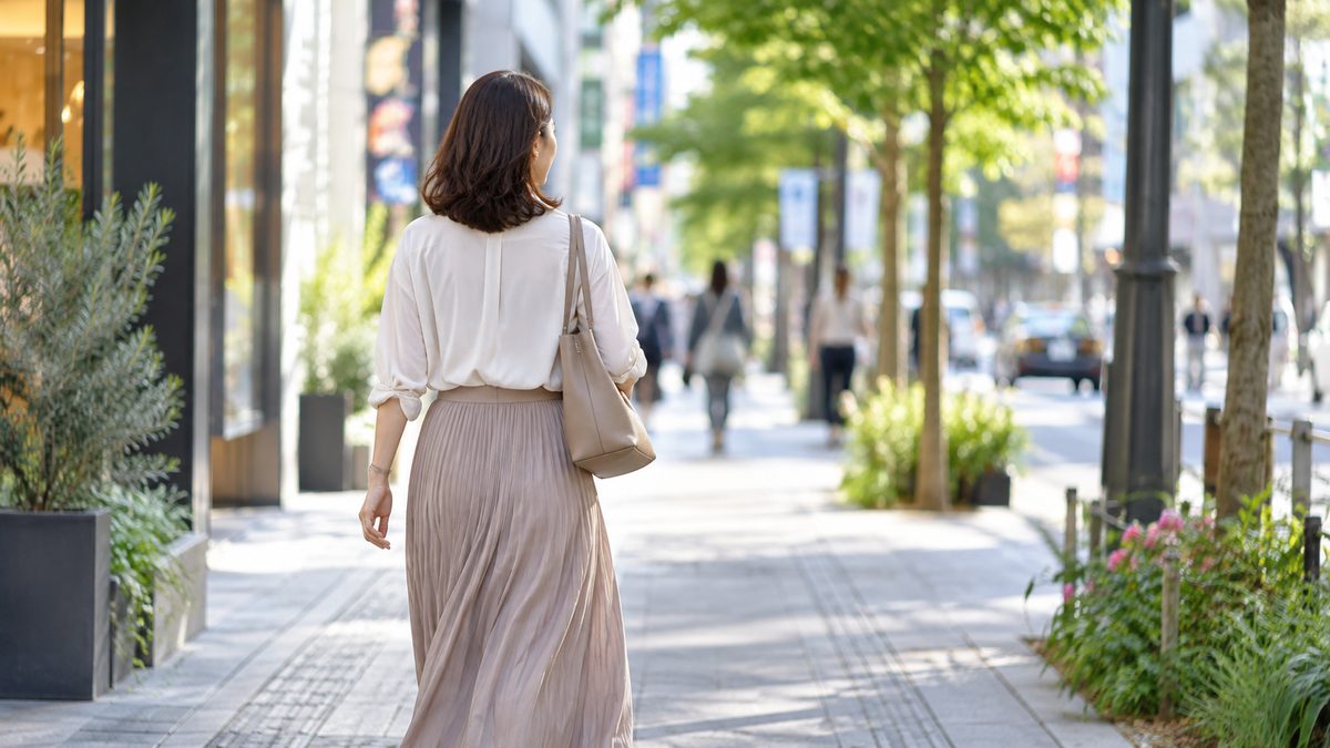 明るい街を一人で歩く40代女性の後ろ姿