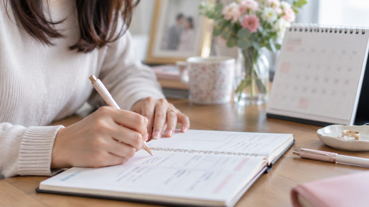 手帳に婚活の予定と期限を書き込んでいる手元