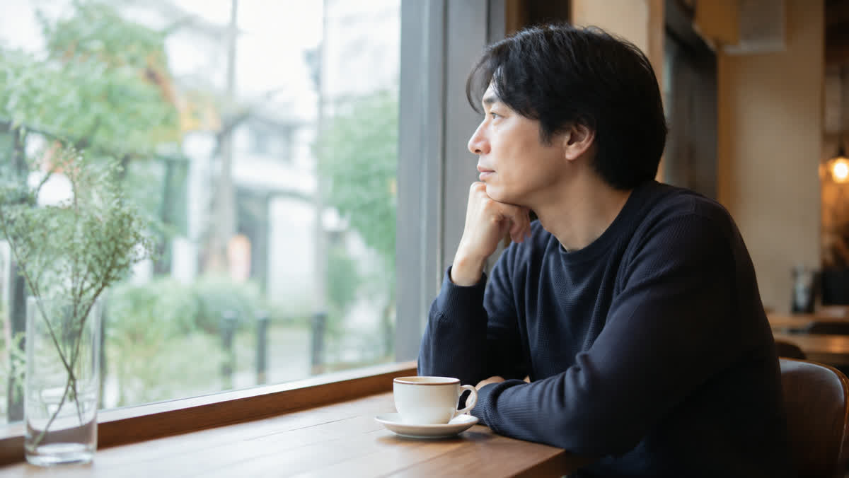 カフェの窓際でひとり考えごとをしている30代の人