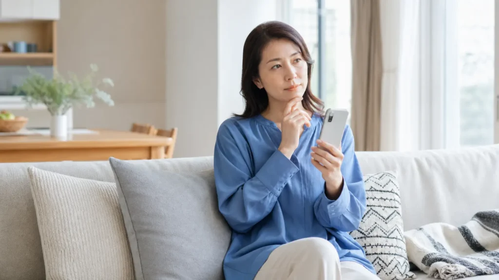 スマートフォンで情報を調べながら考え込む女性