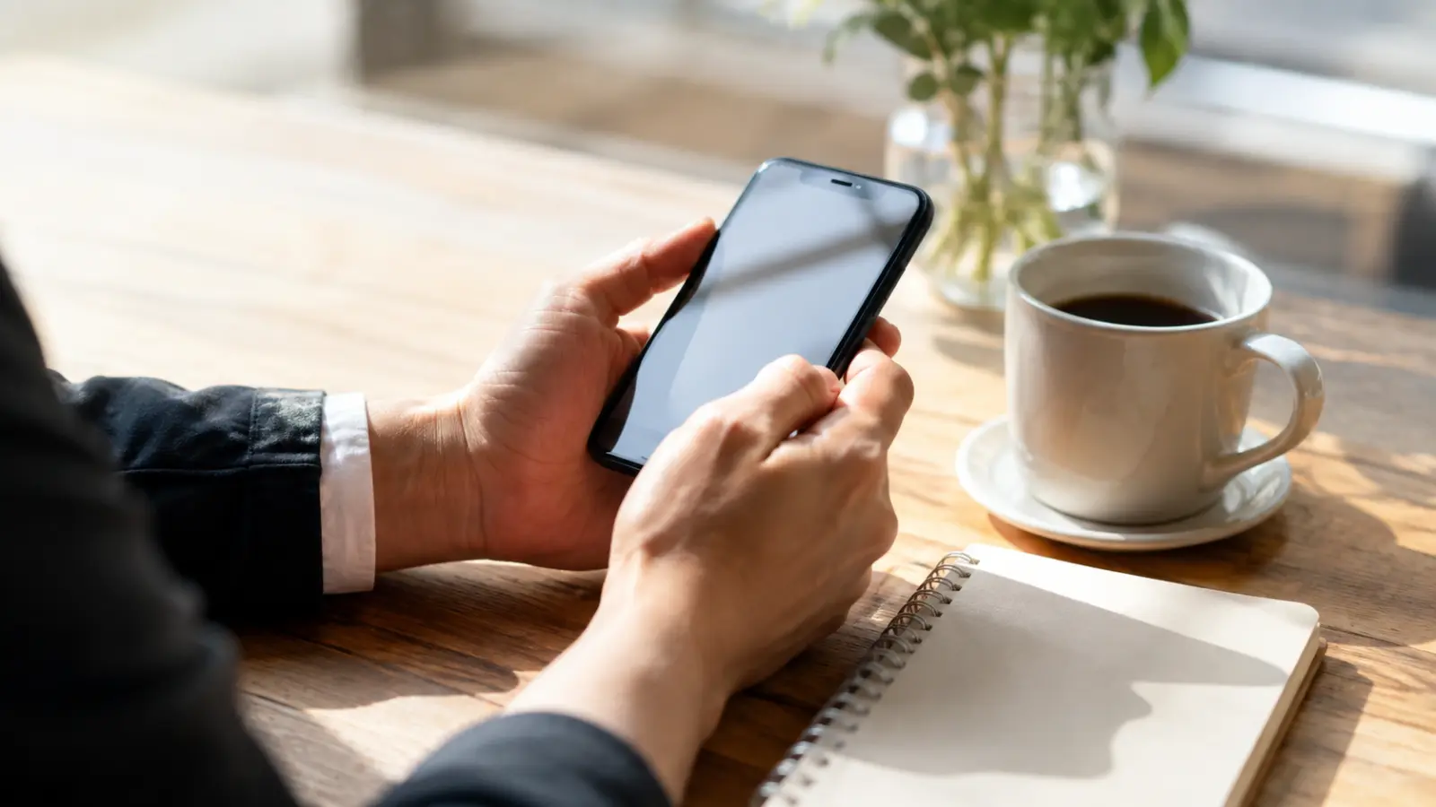 カフェでスマートフォンを操作しながら婚活アプリを見る40代の手元