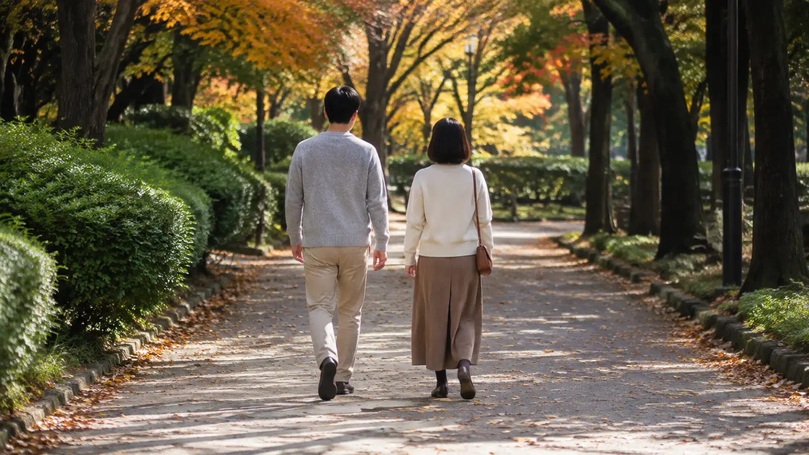 公園を並んで歩く40代の男女の後ろ姿
