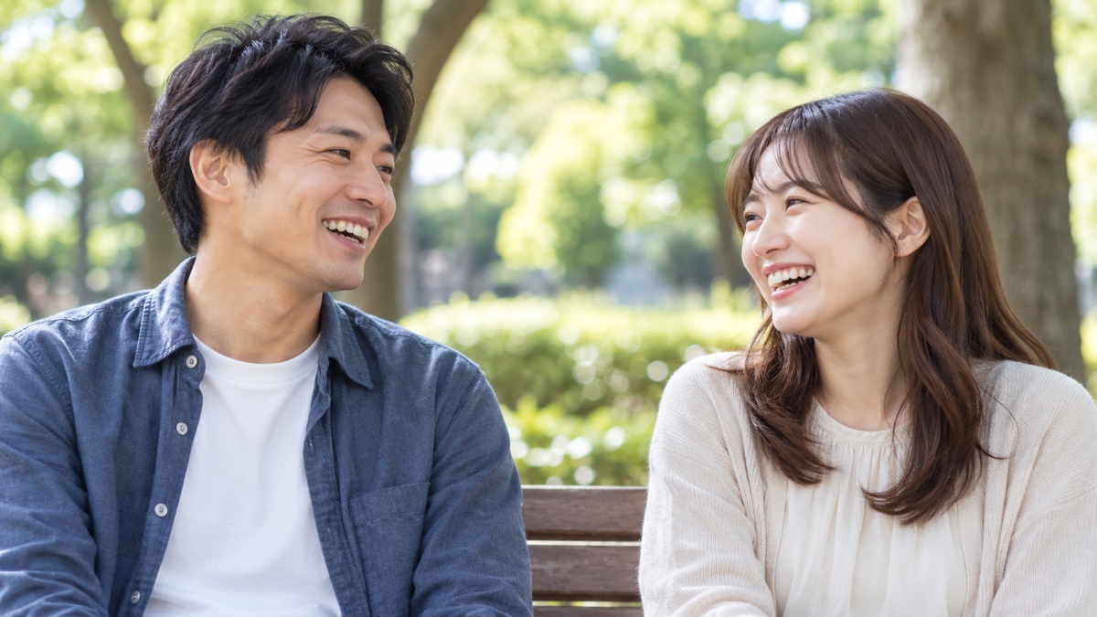 日本の公園のベンチでリラックスして話す30代の日本人男女